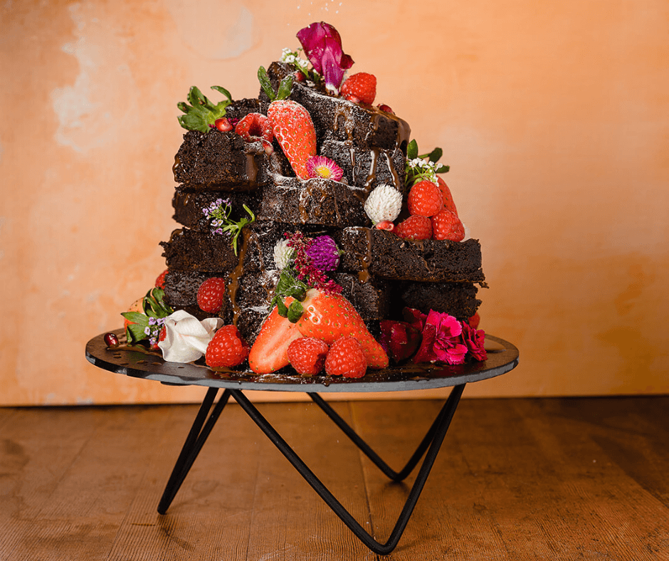 Decadent chocolate brownie cake layered with fresh strawberries, whipped cream and edible flowers