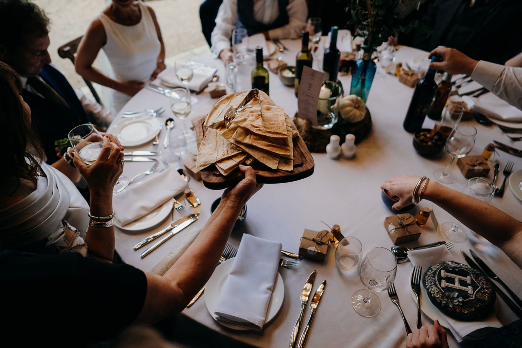 Wedding reception table with guests sharing flatbread, wine and professionally catered dishes